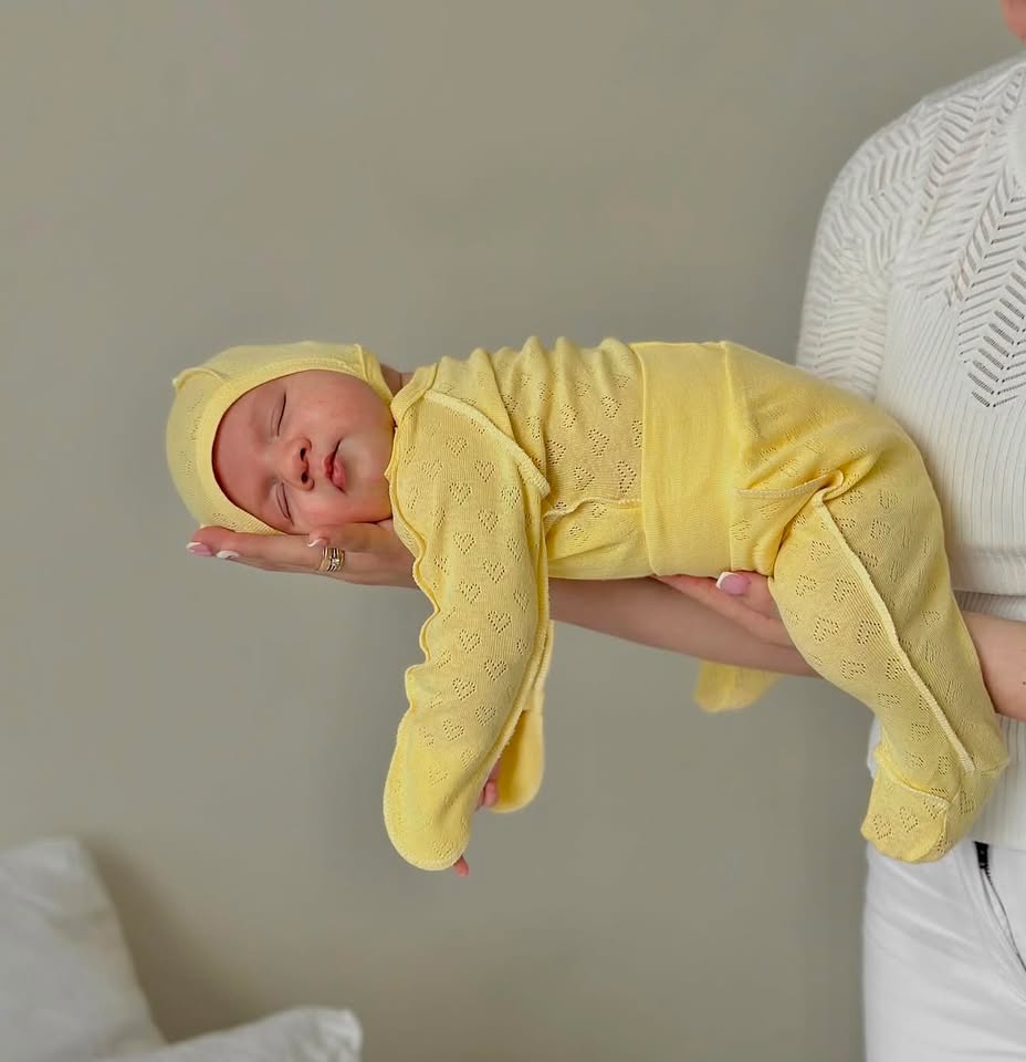 Neonato che dorme indossando il set Liolia giallo con perforazione a cuori